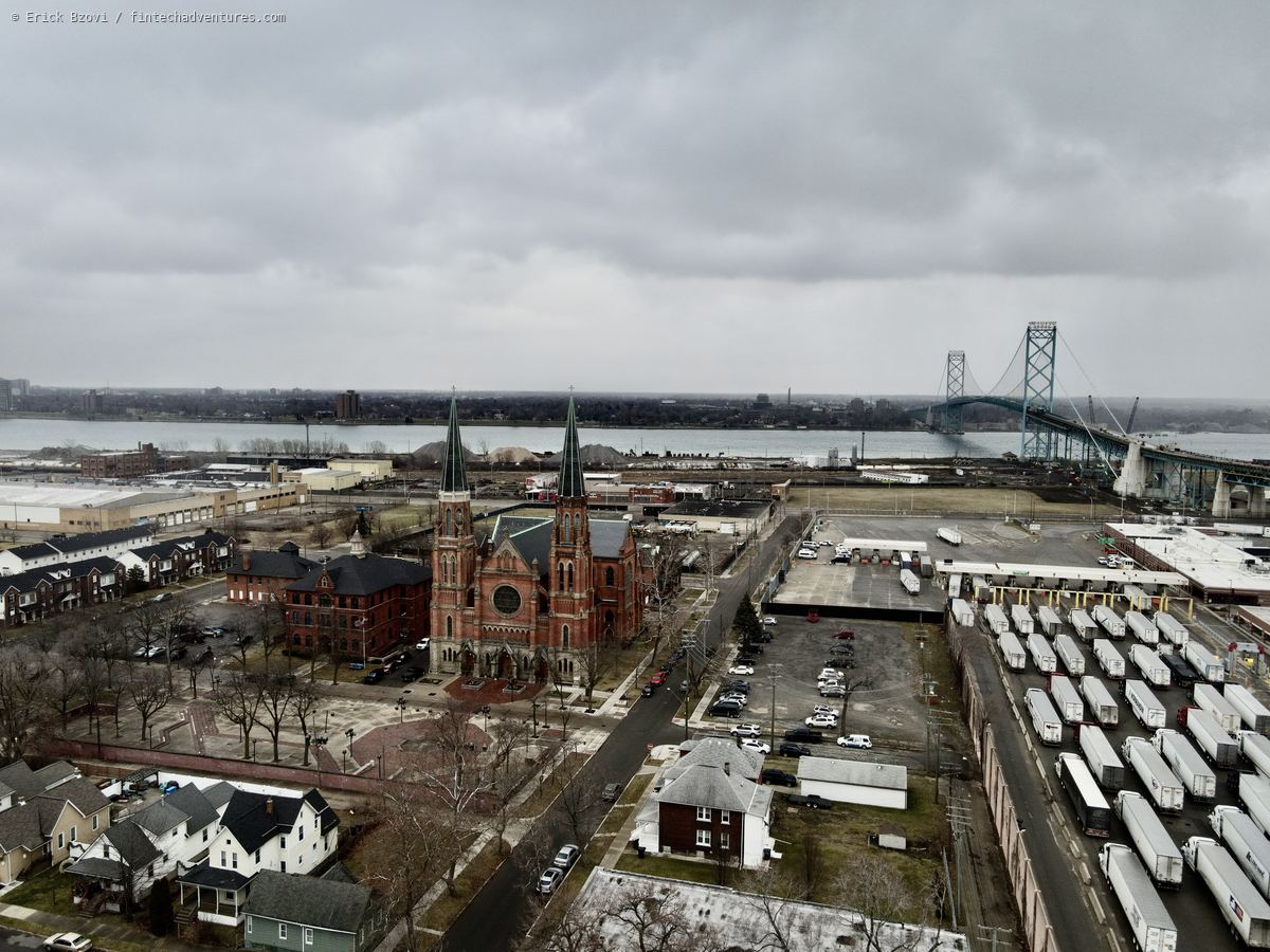 Aerial drone view of the Ambassador Bridge to Windsor with the twin spires of Ste. Anne de Detroit and lines of freight trailers at the border crossing, Michigan