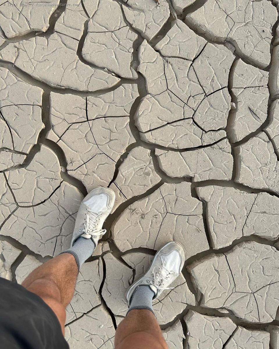Feet standing on cracked dried earth at Death Valley National Park, California