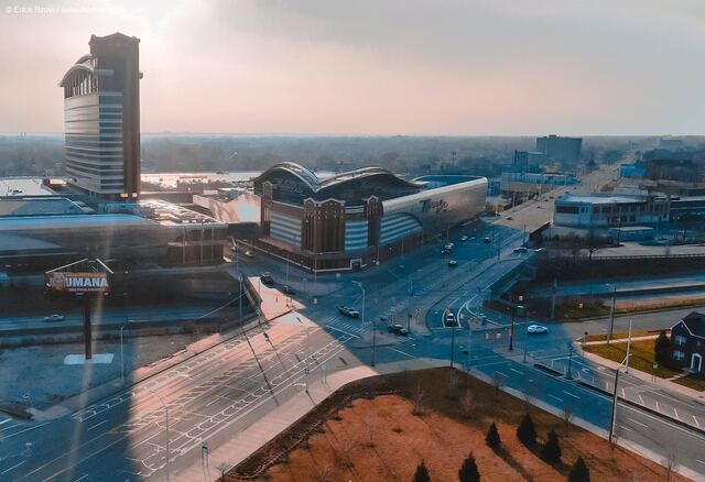 Aerial drone view of MotorCity Casino Hotel and surrounding Detroit cityscape at golden hour with lens flare