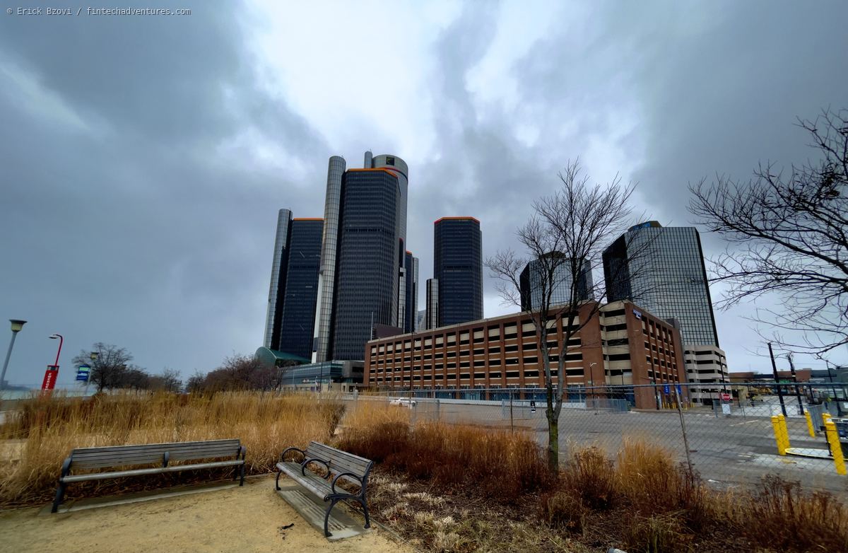 Renaissance Center towers under heavy grey cloud seen from benches on the Detroit riverfront, Michigan