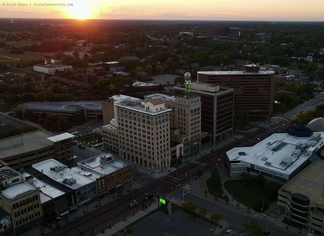 Aerial drone view of downtown Flint at sunset with the University of Michigan Flint campus and Hurley Medical Center on the horizon, Michigan
