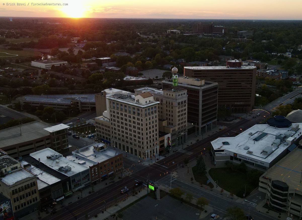 Aerial drone view of downtown Flint at sunset with the University of Michigan Flint campus and Hurley Medical Center on the horizon, Michigan