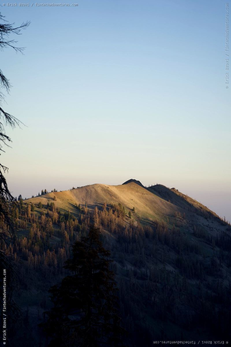 Golden hour light on Lassen Peak with pine forest and volcanic slopes in Lassen Volcanic National Park, California