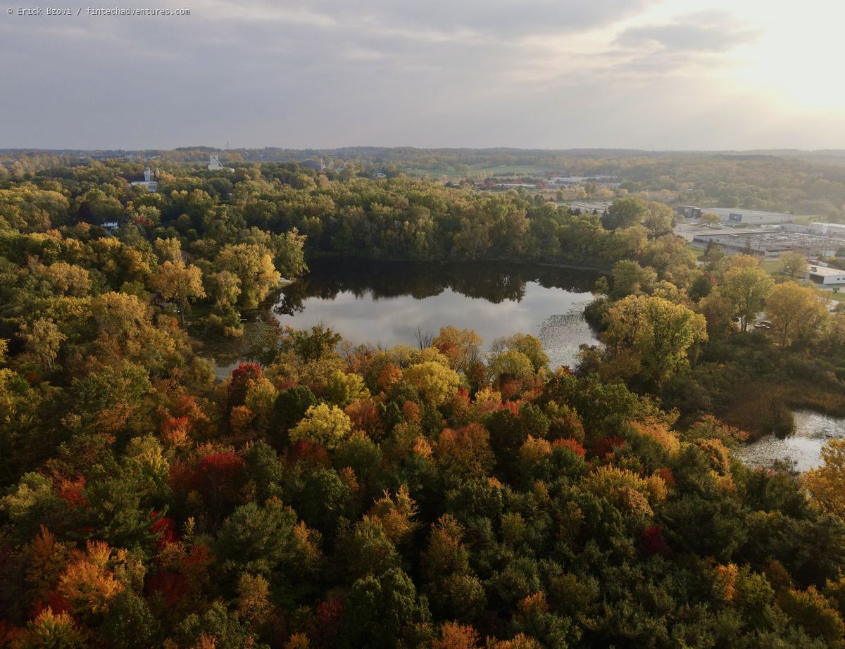 Aerial view of autumn forest color around a small lake at golden hour in Michigan
