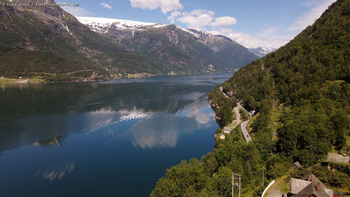 Aerial drone view of a Norwegian fjord with snow-capped mountain reflections in still water
