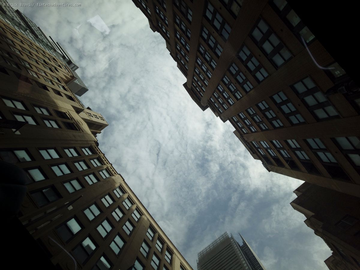 Looking straight up through Manhattan skyscraper canyon with clouds, New York City