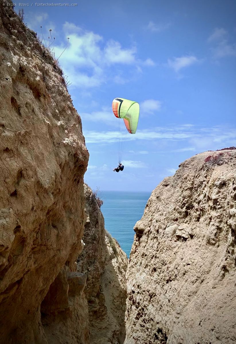Paraglider flying between sandstone coastal cliffs above the Pacific at Torrey Pines, California