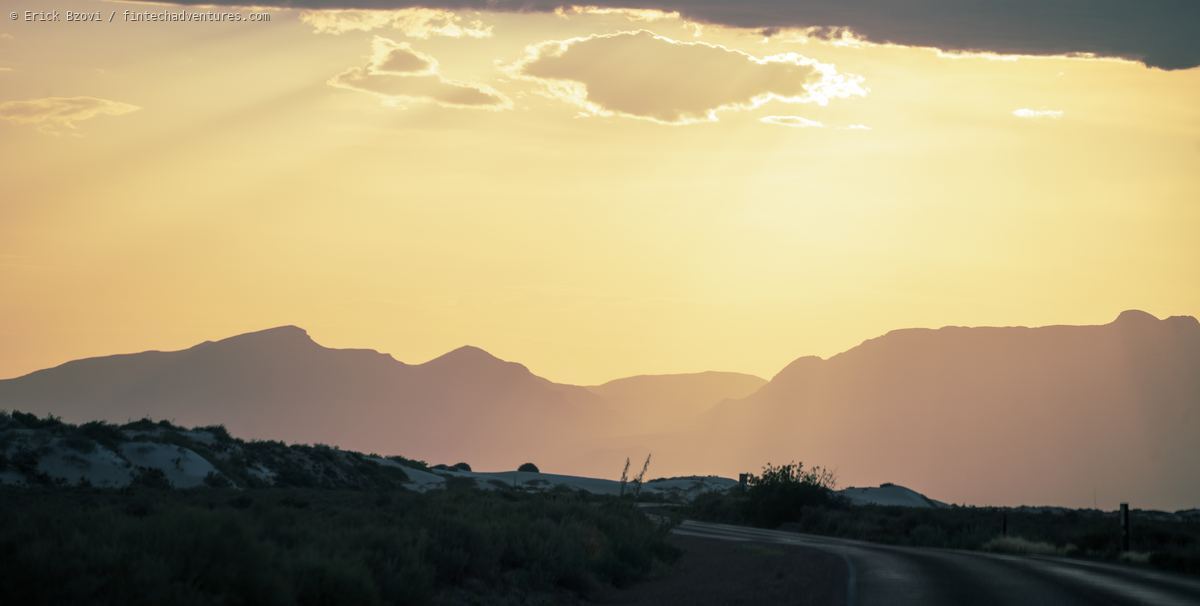 Layered mountain silhouettes at golden sunset with white sand dunes in the foreground, White Sands National Park, New Mexico